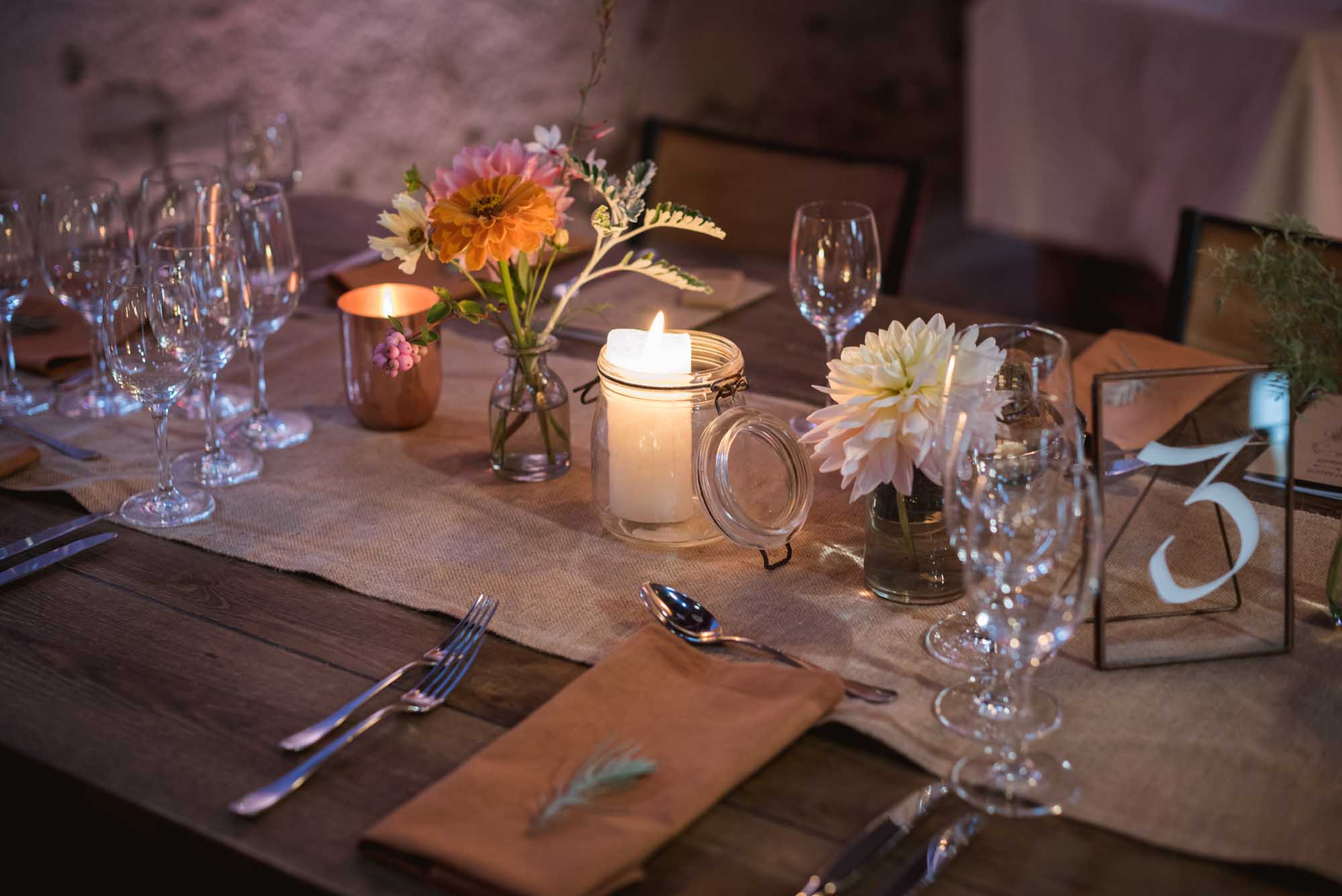 Décoration de table : serviette en lin camel, bougeoirs cuivre et fleurs pêche et rosé